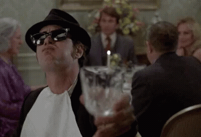 Man In Hat And Sunglasses Holding Water At Dinner Table GIF