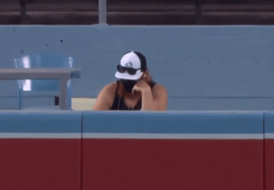 Man In Hat And Sunglasses Sitting In Stadium GIF