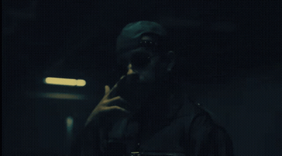 Man In Hat And Sunglasses Smoking Cigarette In Dark Room GIF
