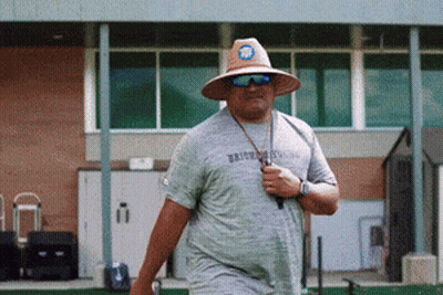 Man In Hat And Sunglasses Walking In Front Of Brooklyn Building GIF
