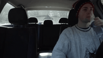 Man In Hat And Sweater Drinking Water In Back Seat GIF