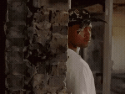 Man In Hat And White Shirt In Front Of Brick Wall GIF