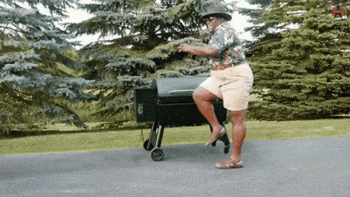 Man In Hat Balancing On One Leg At Grill GIF