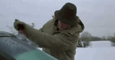 Man in Hat Cleaning Windshield in Snow