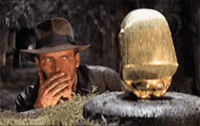 Man In Hat Covering Mouth Beside Large Gold Object GIF