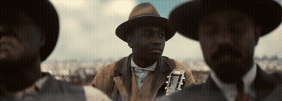 Man In Hat Holding Guitar Next To Two Men GIF