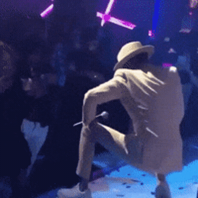 Man In Hat Kneeling On Stage With Microphone GIF