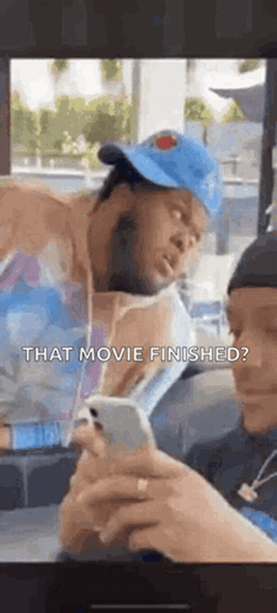 Man In Hat Looking At Phone While Another Watches GIF
