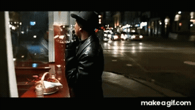 Man In Hat Looking Out Window At City Night GIF