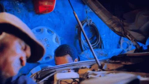 Man In Hat Looking Under Hood In Garage GIF