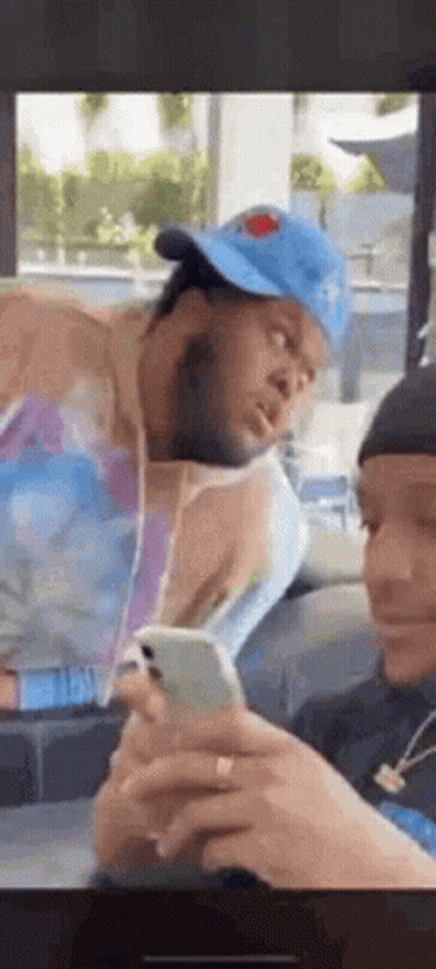 Man In Hat On Cell Phone, Another Man Watching GIF