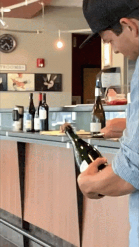 Man In Hat Opening Wine In Front Of Tomorrow Sign GIF