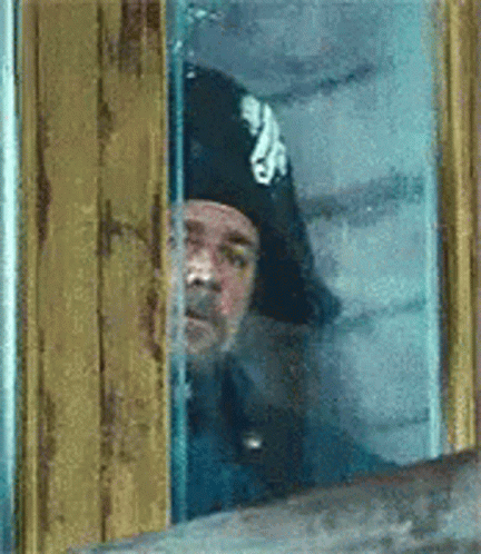 Man In Hat Peeking Out Window GIF