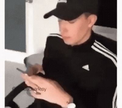 Man In Hat Sitting In Chair Looking At Phone GIF