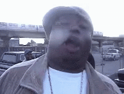 Man In Hat Smoking Cigarette In Parking Lot GIF