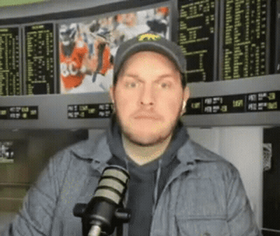 Man In Hat Standing At Microphone In Front Of Scoreboard GIF