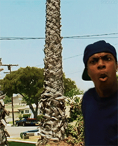 Man In Hat Standing By Palm Tree In Residential Area GIF