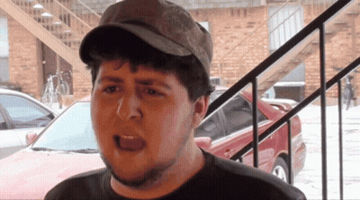 Man In Hat Standing In Front Of Brick Building GIF