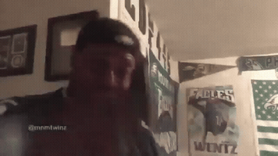 Man In Hat Standing In Front Of Poster Wall GIF