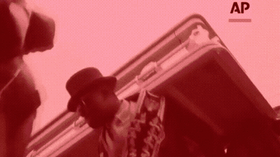 Man In Hat Standing Next To Briefcase With Letters AP GIF