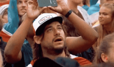 Man In Hat Taking Selfie In Crowd GIF