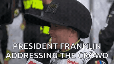 Man In Hat Talking Into Microphone Addressing Crowd GIF