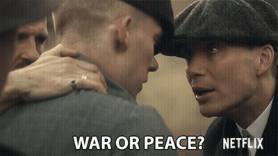 Man In Hat Talks To Another Man Saying War Or Peace GIF