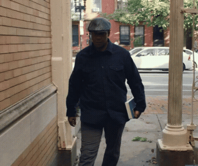 Man In Hat Walking Down Sidewalk GIF