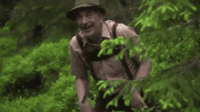 Man In Hat Walking Through Forest GIF