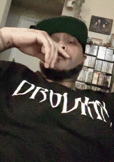 Man In Hat Wearing Dbolmn Shirt Smoking Cigarette GIF