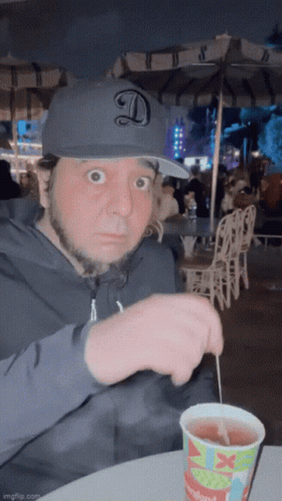 Man In Hat With Letter D Sitting At Table With Disneyland Drink GIF