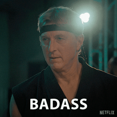 Man In Headband Standing In Front Of Badass Sign GIF