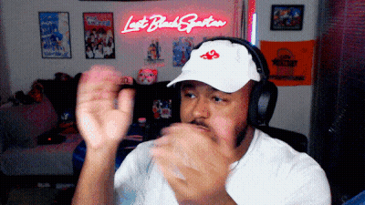 Man In Headphones And White Hat In Front Of Lost Black Spartan Neon Sign GIF
