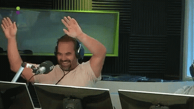 Man In Headphones Sitting At Microphone With Hands Up GIF