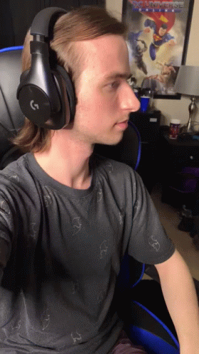 Man In Headphones Sitting In Front Of Justice League Poster GIF