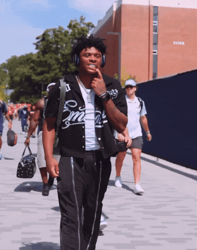 Man In Headphones Wearing Smith Shirt Walking Down Street GIF