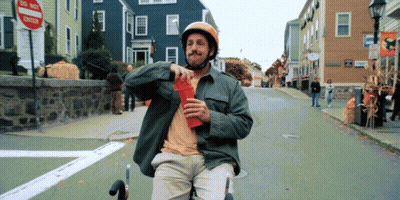 Man In Helmet Riding Scooter Down Street GIF