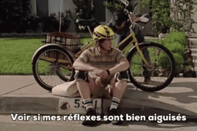 Man In Helmet Sitting On Curb Next To Bicycle Saying Voir GIF