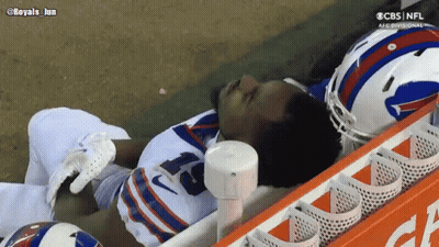 Man In Helmet Talks To Another Man Watching CBS Football GIF