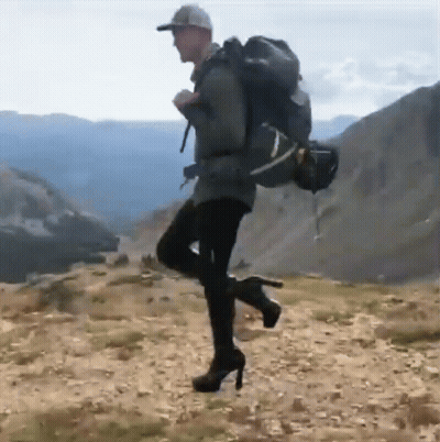 Man In High Heels And Backpack On Hill GIF
