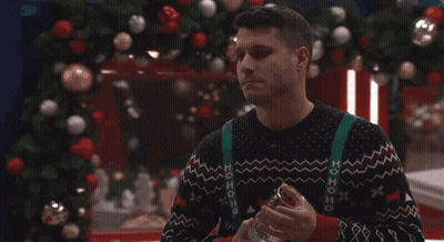 Man In Ho Ho Ho Sweater Holding Glass By Christmas Tree GIF