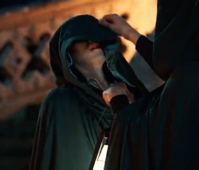 Man In Hooded Cape Holding Lantern Talking To Another Man GIF