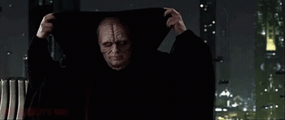 Man In Hooded Cloak By Window In Dark Room GIF
