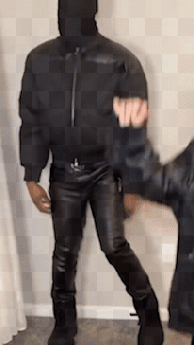 Man In Hooded Jacket And Leather Pants Next To Another Man GIF
