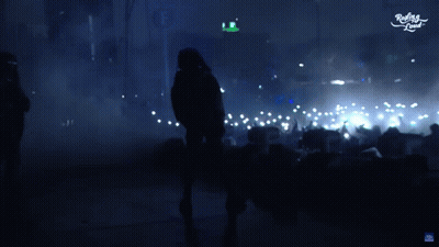 Hombre con chaqueta con capucha bailando frente a la multitud dice muy fuerte GIF
