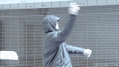 Man In Hooded Jacket Dancing In Front Of Grid Wall GIF