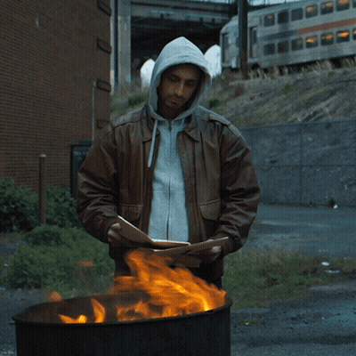 Man In Hooded Jacket Standing In Front Of Fire GIF
