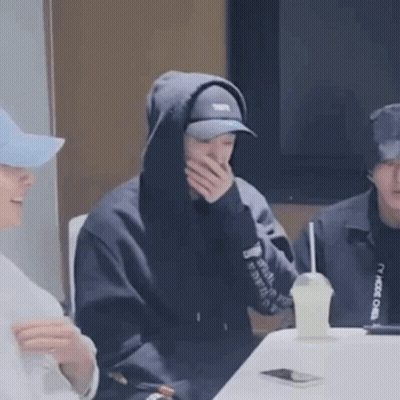 Man In Hoodie And Hat Sitting With Drink GIF