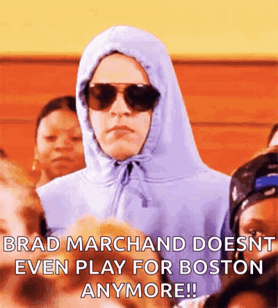 Man in Hoodie and Sunglasses Sitting in Crowd