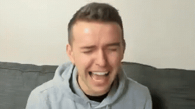 Man In Hoodie Laughing On Couch GIF